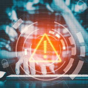 Graphic of a person sitting at a keyboard with a hologram of an alert signal superimposed. Photo credit: Adobe Stock