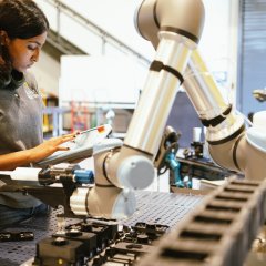 Photo of an ARM Institute employee working on a robotic arm.