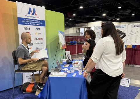 Photo from the Manufacturing USA SkillsUSA booth of students talking to a staff member.