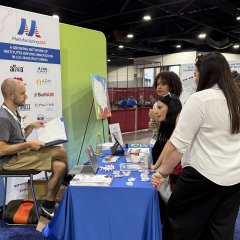 Photo from the Manufacturing USA SkillsUSA booth of students talking to a staff member.