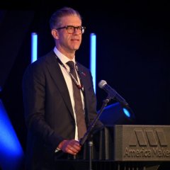 Photo of John Wilczynski standing at a podium speaking at America Makes' MMX event.