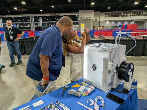 Photo from the Manufacturing USA booth at SkillsUSA of visitors checking out the 3D printer