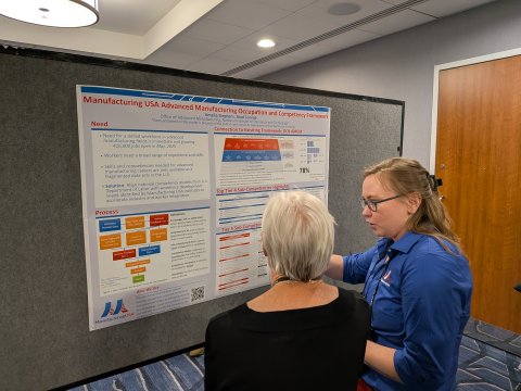 Photo of a Manufacturing USA representative talking to a visitor about the Advanced Manufacturing Occupation and Competency Framework