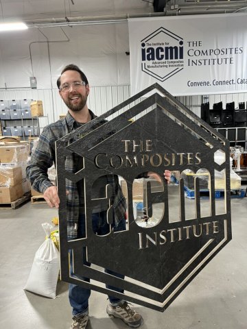 Photo of Vitriform3D CEO, Alex Stiles, holding up a composite sign of the IACMI logo
