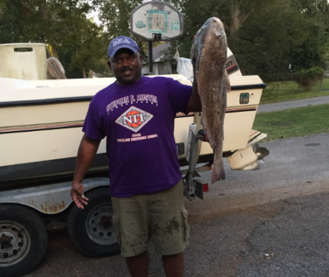 Photo of Melvin White holding a large fish next to a boat