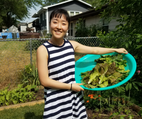 Photo of Niki Kim standing in a garden with a large bowl of lettuce