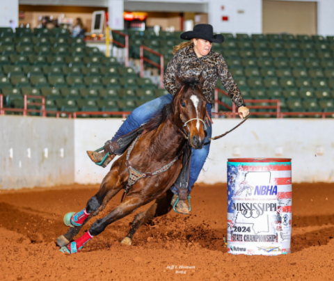 Photo of Courtney Taylor barrel riding with her horse at a rodeo