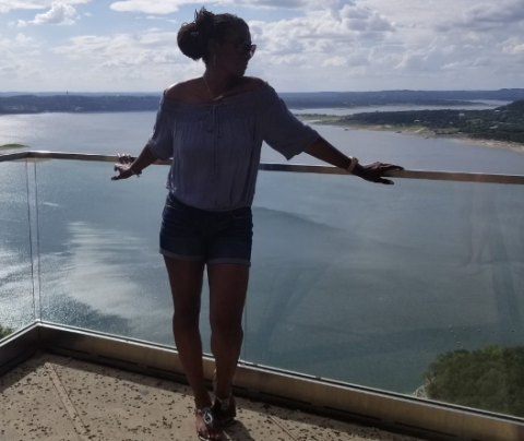Photo of Jacqui Hall standing against a glass railing with a waterway behind her below